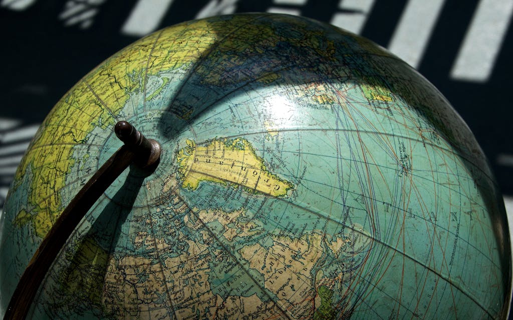 BinusCX A detailed vintage globe showcasing northern regions with visible longitude and latitude lines.