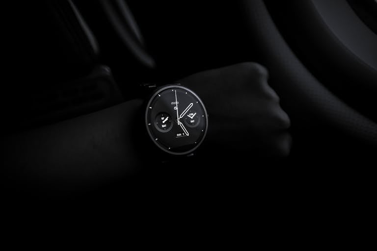 Simbramento A sleek Moto 360 smartwatch showing time on a wrist in a dimly lit setting, emphasizing its modern design and technology.
