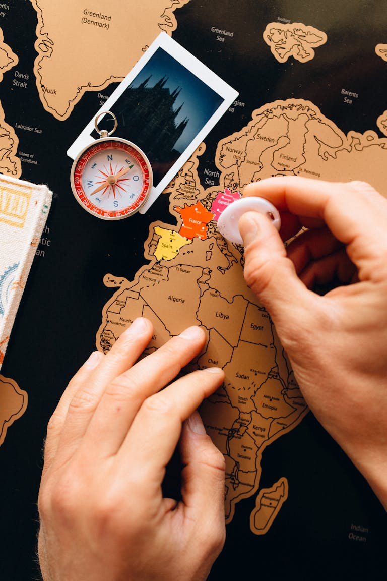 Blazertje: The Ultimate Guide to This Timeless Fashion Essential 2026 Close-up of hands scratching a travel map, featuring a compass and polaroid, symbolizing travel planning.