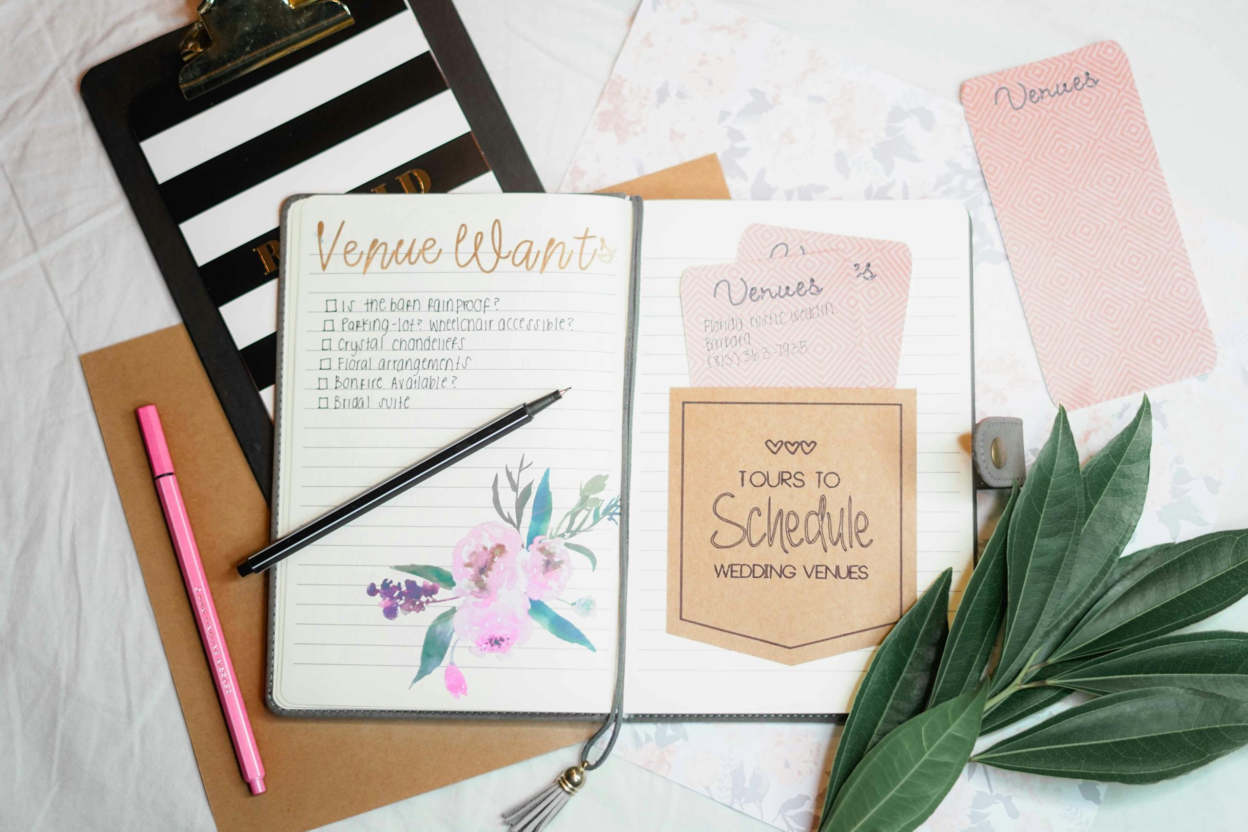 Bastinews.xyz Flat lay of wedding planning materials including a journal, leaves, and stationery.