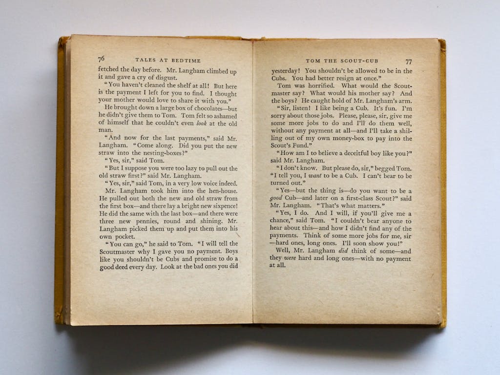 BinusCX  Kinervus Vintage book opened to pages 76-77, displaying classic literature text in soft lighting.