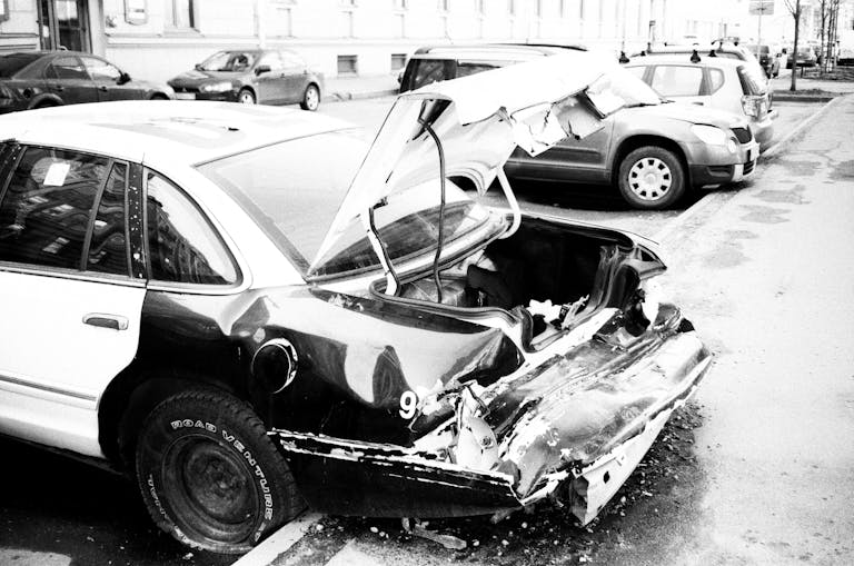 MC Lyte Car Crash A black and white photo of a wrecked car on an urban street, highlighting vehicle damage.