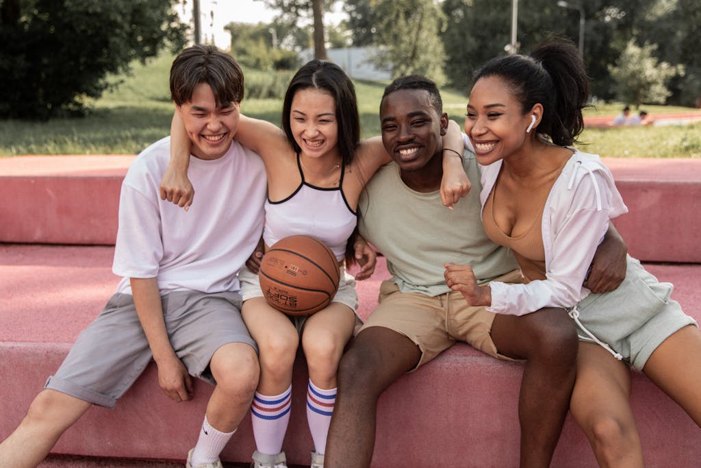 JuntosSeguros A diverse group of young friends sharing joyful moments outdoors with a basketball.