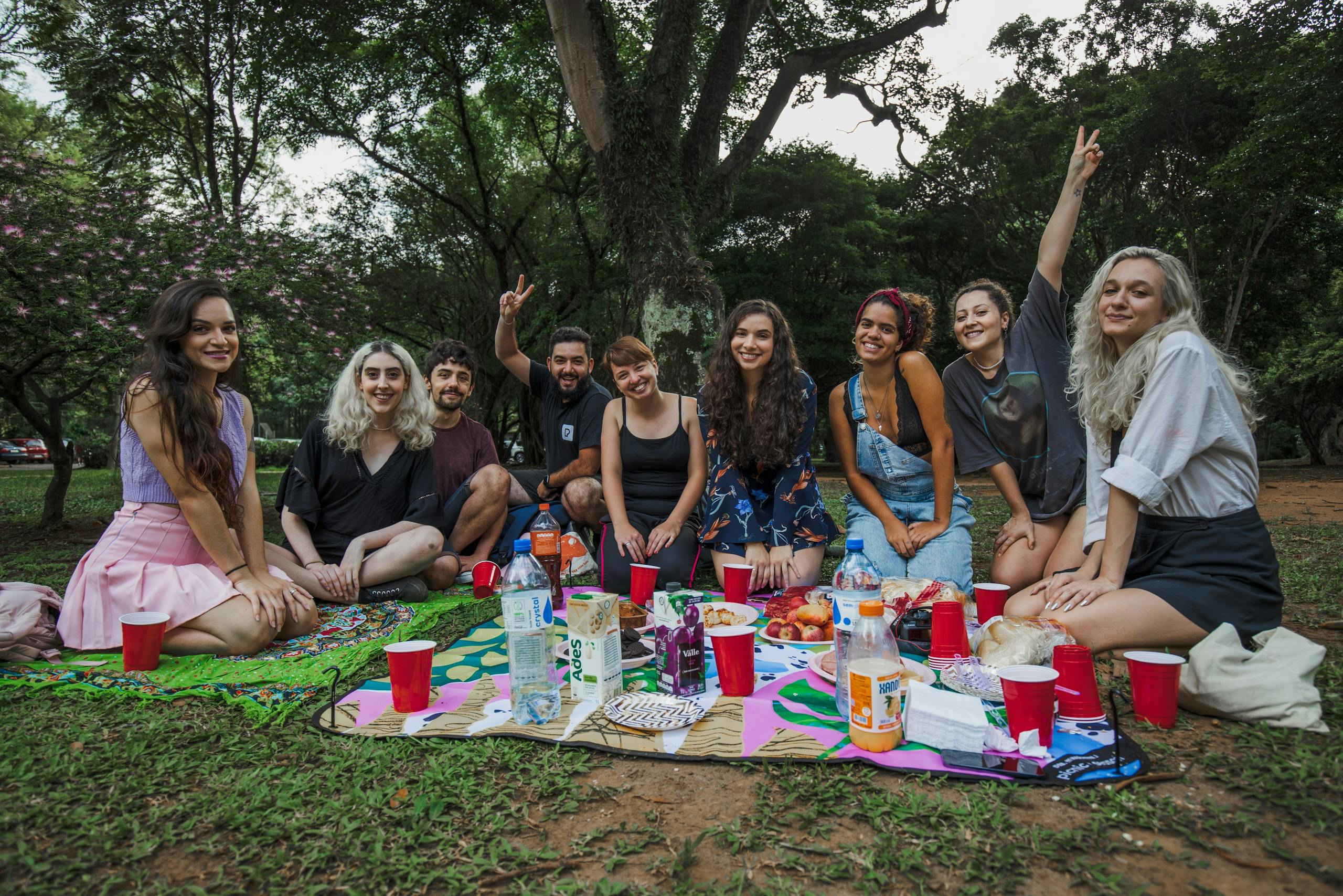 SocialMediaGirls Forum A group of young adults enjoying a fun picnic in a park, smiling and sitting together.