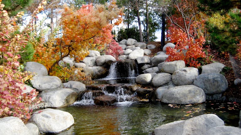 Valplekar Beautiful autumn stream flowing through a peaceful rock garden surrounded by vibrant foliage.