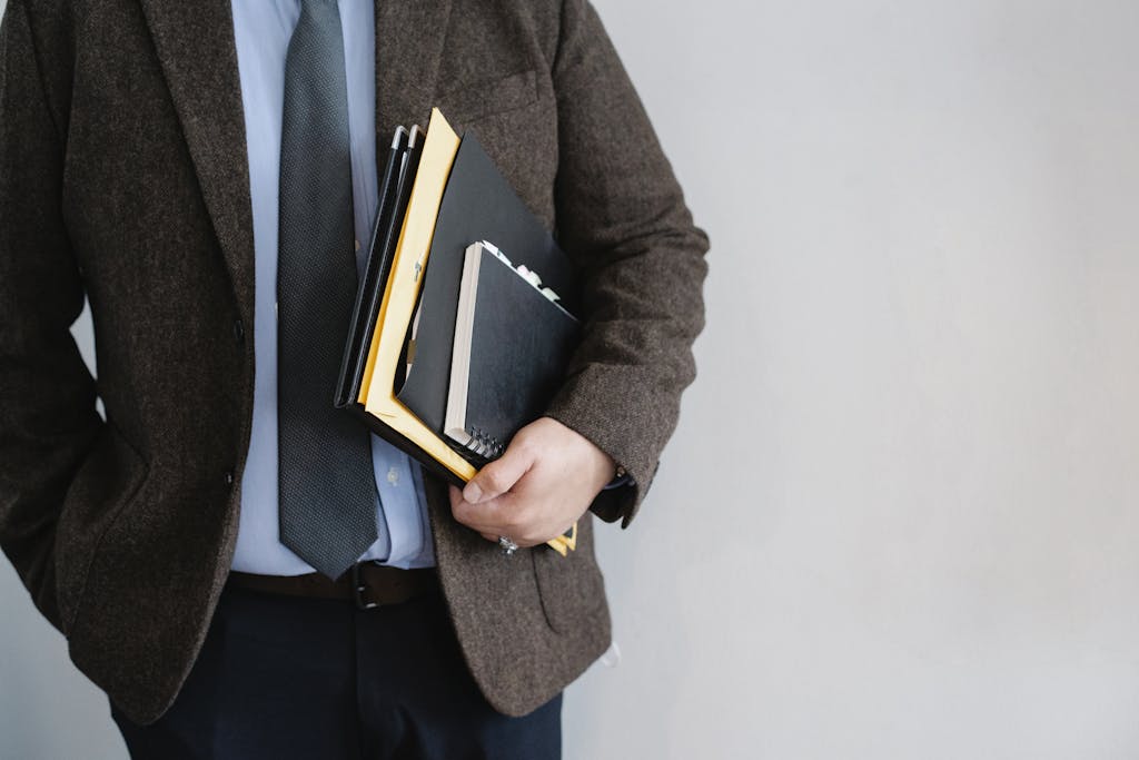 Blazertje Business professional in a suit holding various folders and notebooks indoors.