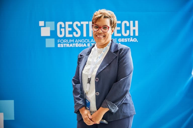 Texas Hunting Forum Businesswoman smiling in front of blue backdrop at trade fair event, embodying leadership and professionalism.