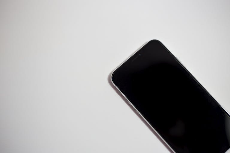 uitly.blog Close-up of a smartphone with black screen on a white background, perfect for technology themes.