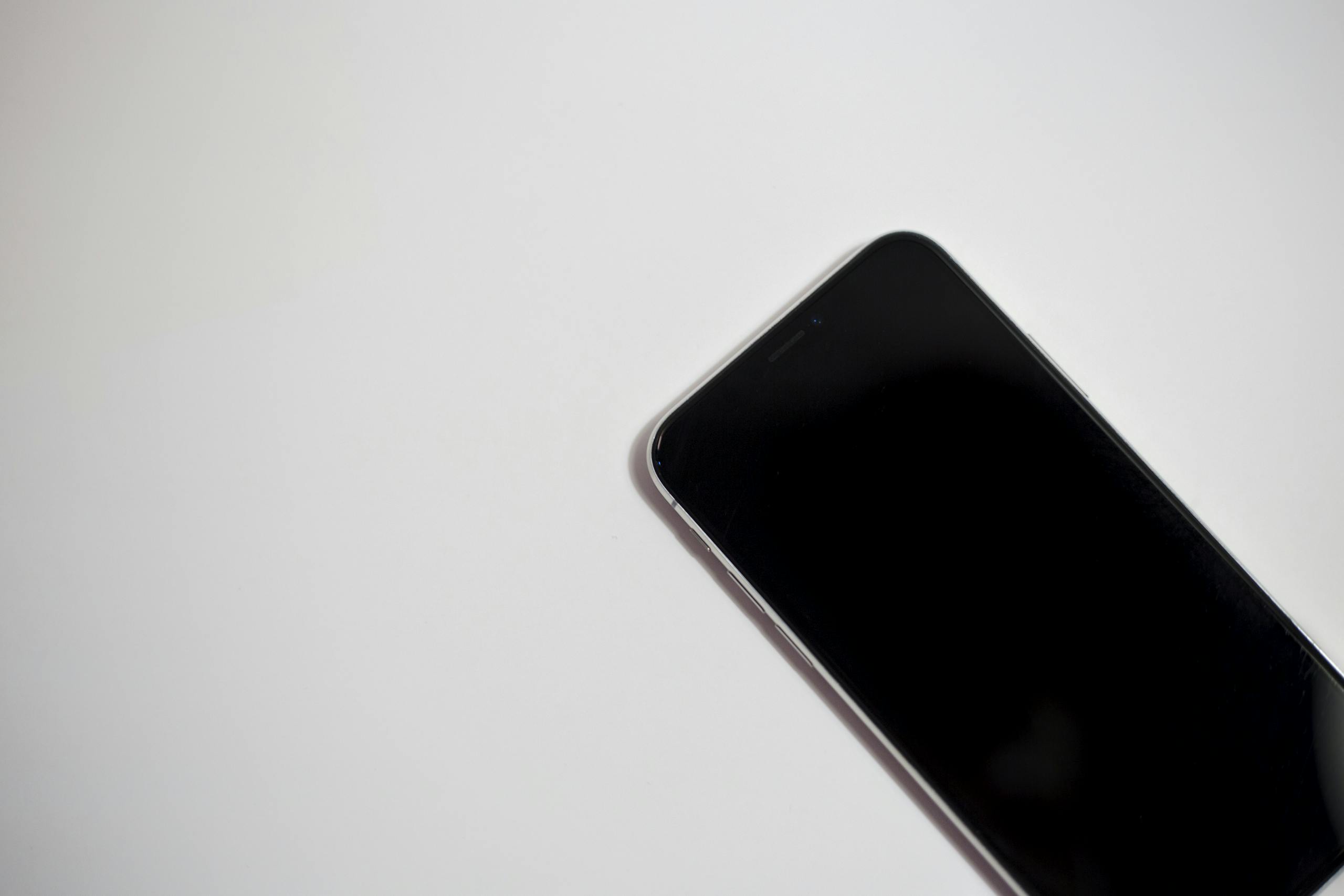 uitly.blog Close-up of a smartphone with black screen on a white background, perfect for technology themes.