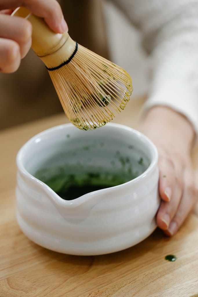 Bin Matcha Close-up of bamboo whisk and white bowl during traditional matcha tea preparation. Perfect for lifestyle and culinary themes.
