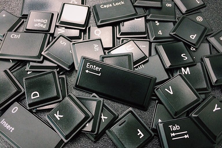 Fetid Key OSRS Close-up of scattered black computer keyboard keys on a surface, showcasing various letters and symbols.
