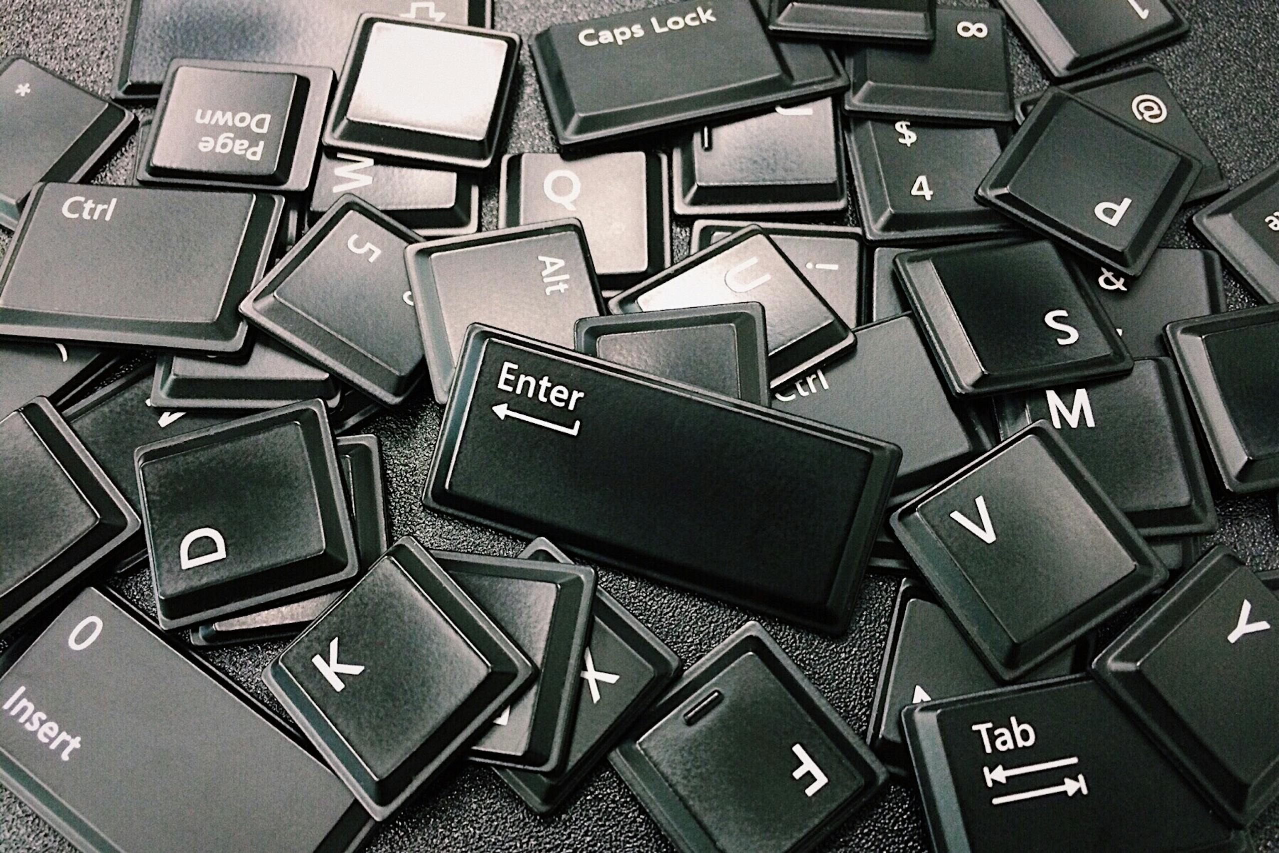 Fetid Key OSRS Close-up of scattered black computer keyboard keys on a surface, showcasing various letters and symbols.
