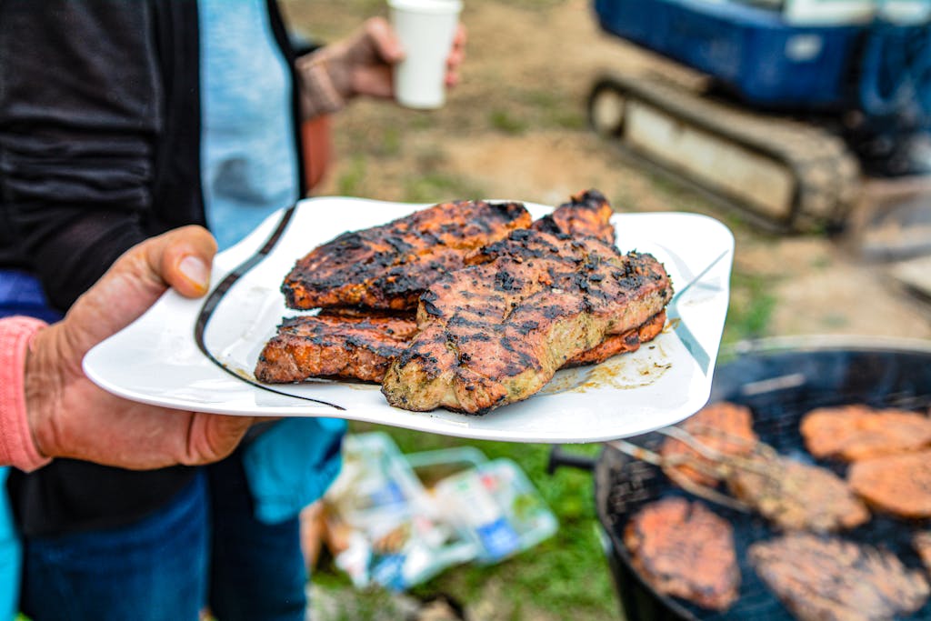 Weber Grillvorführung Delicious grilled steak served on a plate at an outdoor barbecue gathering.