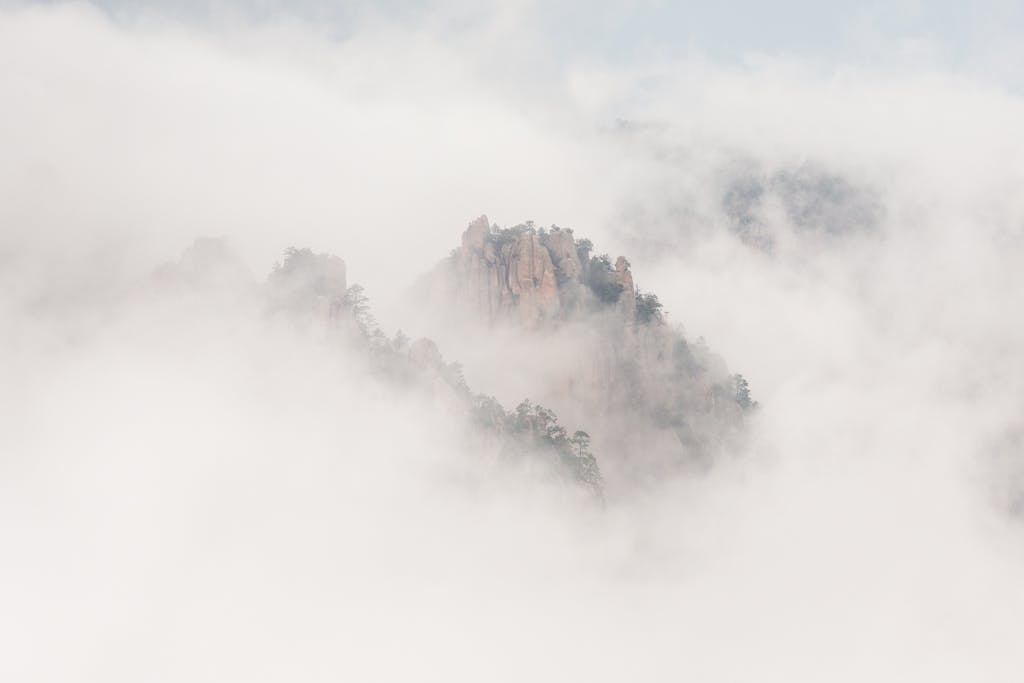 Exploring Edivawer Ethereal view of Barranca del Cobre mountains shrouded in mist and clouds, creating a serene landscape.