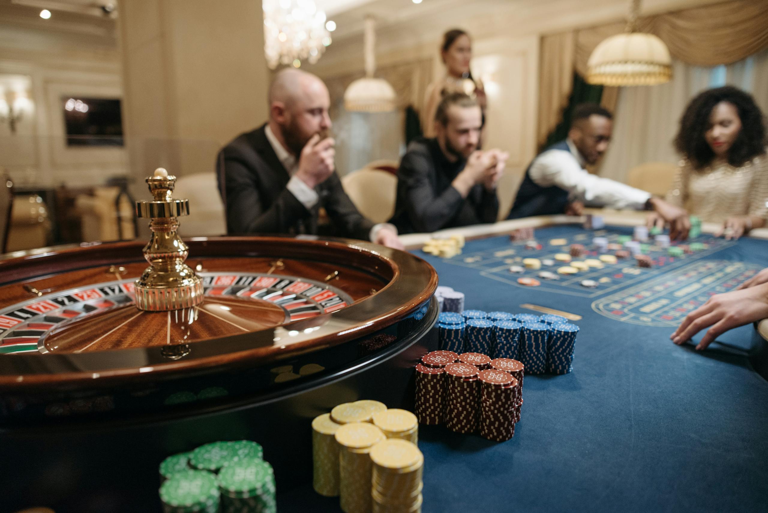 www.ribitup.com People enjoying a roulette game in an upscale casino setting with chips and a roulette wheel.