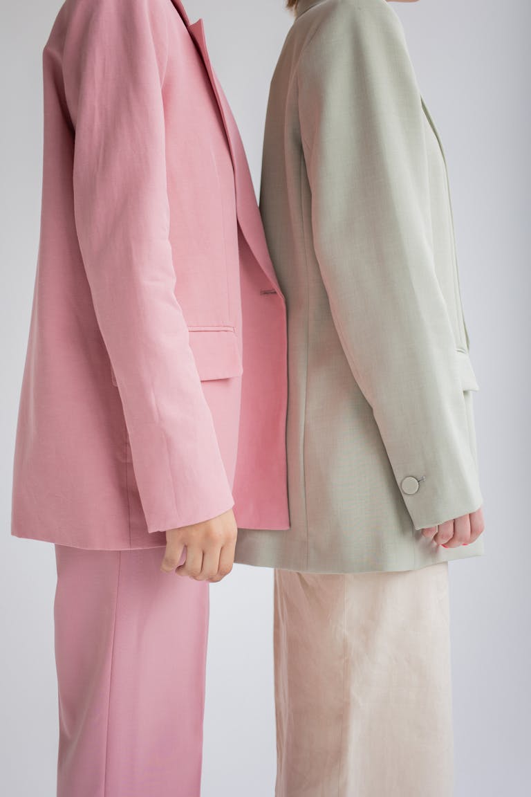 Dojen Moe Side view of crop anonymous female models wearing similar trendy suits standing together against gray background