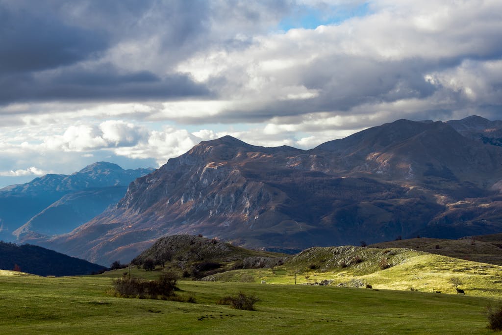 Beautiful Stunning view of the mountains and green fields under a cloudy sky in Žabljak, Montenegro.
