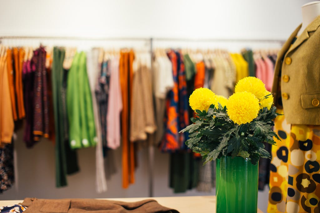 Shop Spring Vase Vibrant clothing racks in a boutique with a floral centerpiece.