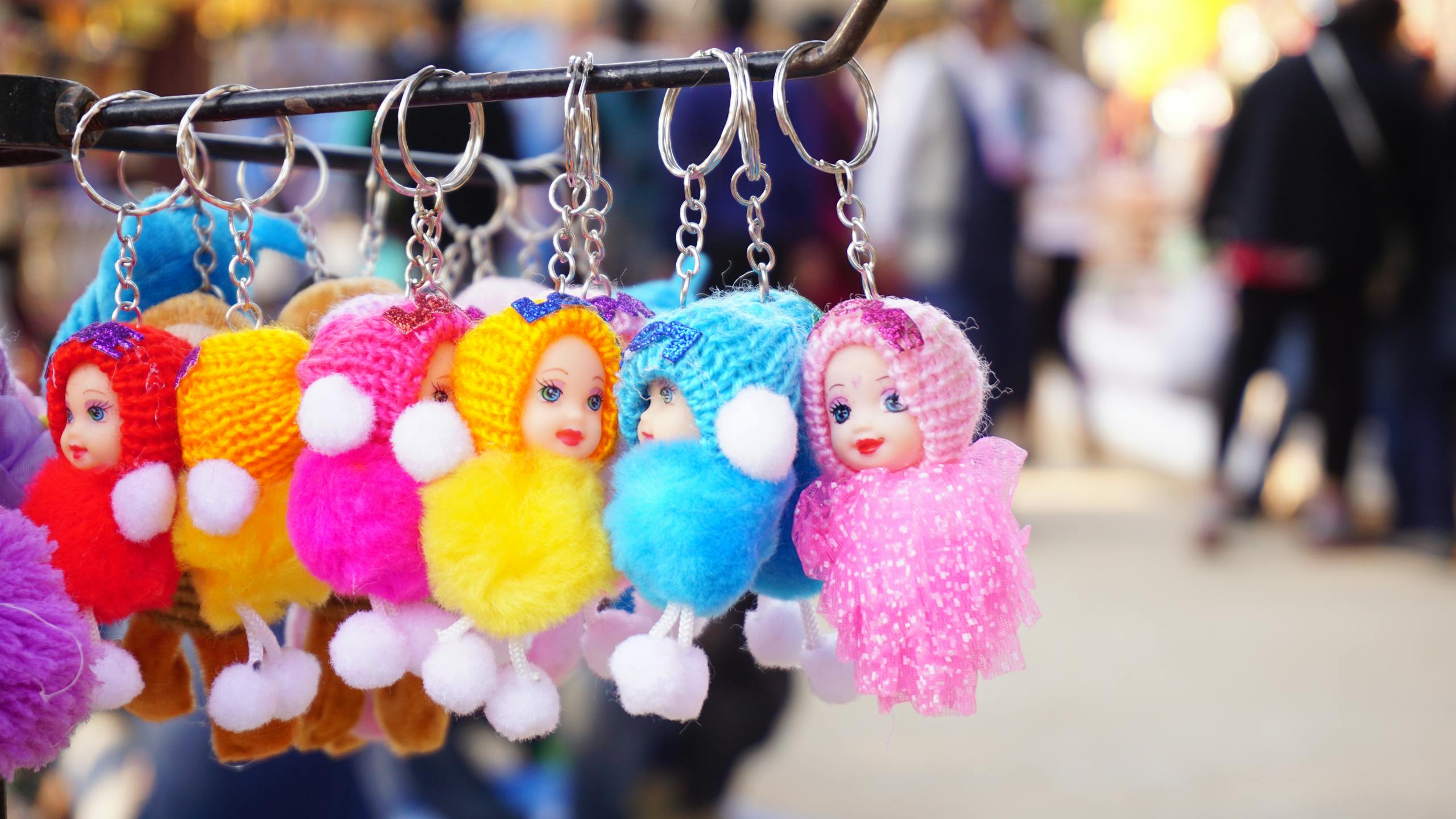 Messeregge Vibrant knitted doll keychains hanging on a rack, perfect for decorative purposes.